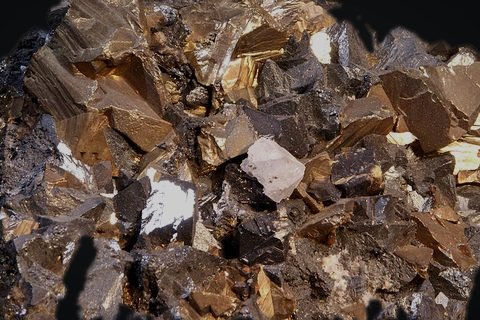 Chalcopyrite, a copper ore, with bright metallic crystals on dark rock